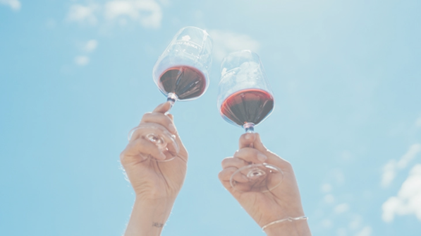 Raising two red wine glasses to the sky