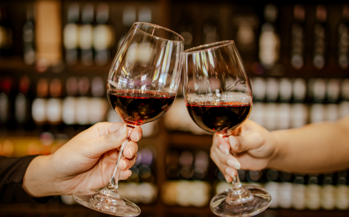 Two red wine glasses clinking
