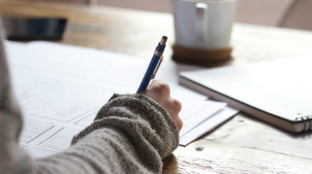 A person writes at a desk